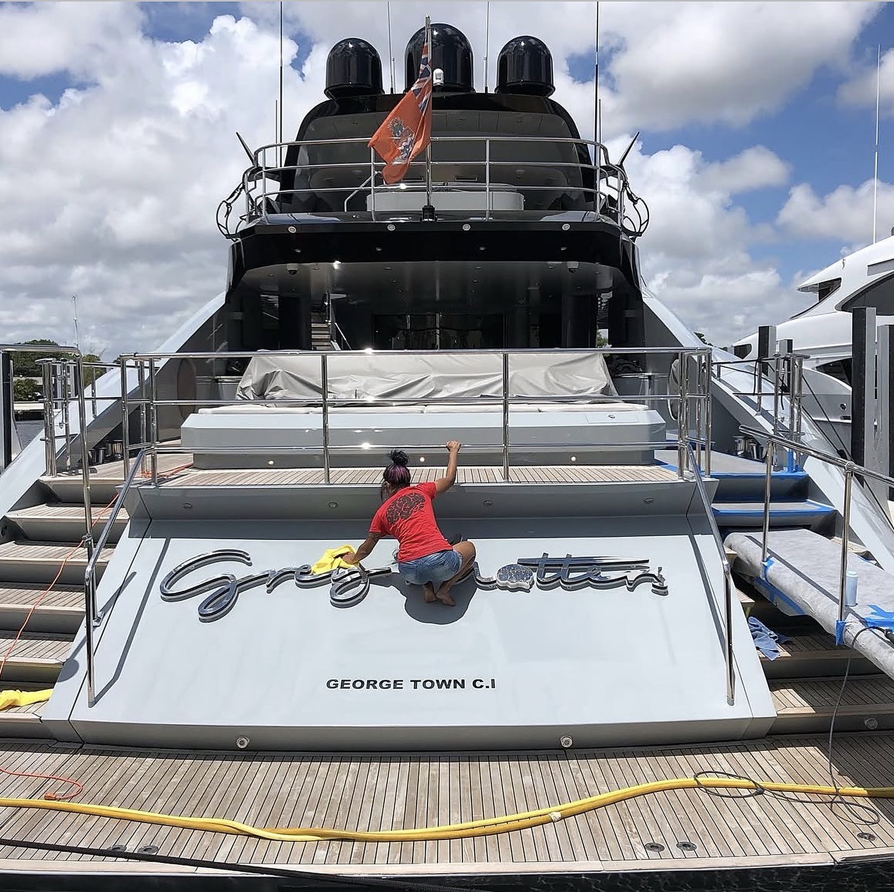 Detailer polishing the swim platform of a large motor yacht